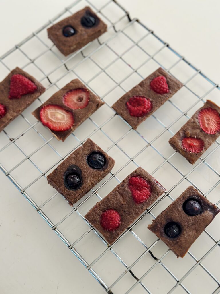 Cukormentes bababarát brownie kockák hűlőrácson, tetején eper, málna és áfonya