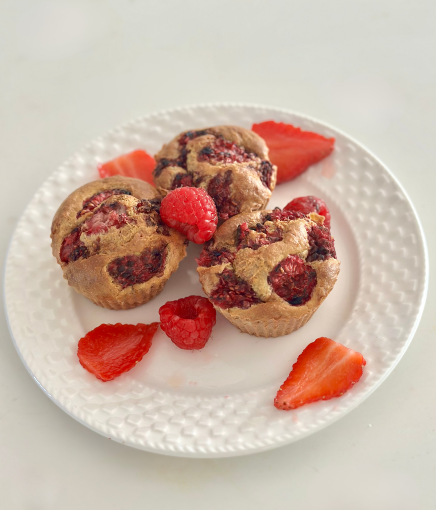 Cukormentes epres-málnás baba muffin fehér tányéron, friss eper- és málnaszeletekkel körítve