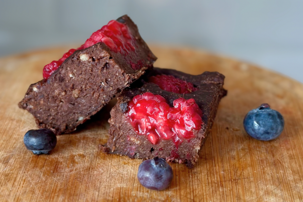 Két szelet csokis brownie málnával és áfonyával fatálon