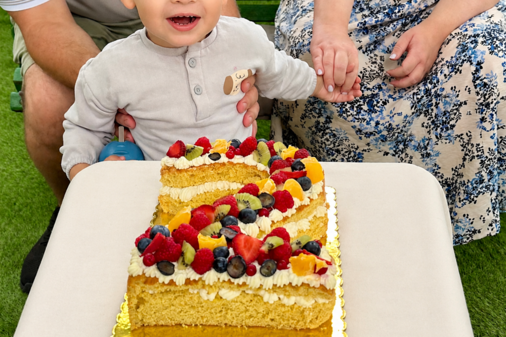 Kisgyermek előtt tálalt házi készítésű kettes számtorta friss gyümölcsökkel